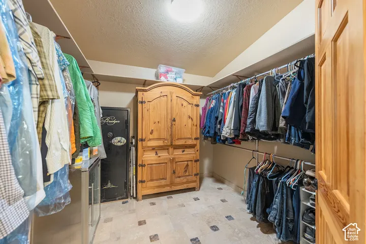 Walk-in closet with extensive hanging rods, built-in shelving, tiled flooring, and a recessed ceiling light