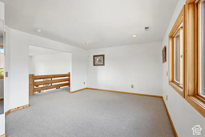Carpeted room with recessed lighting and natural wood window frames