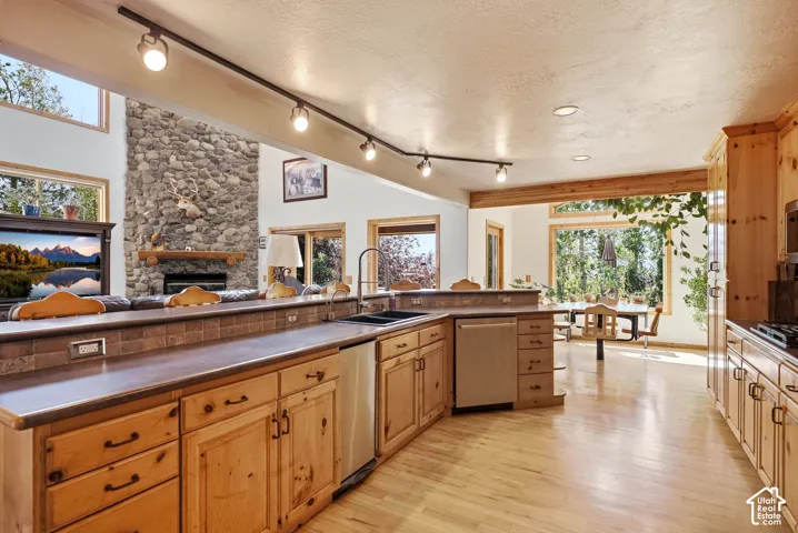 Open-concept kitchen featuring wood-finish cabinetry, stainless steel appliances, and a raised countertop