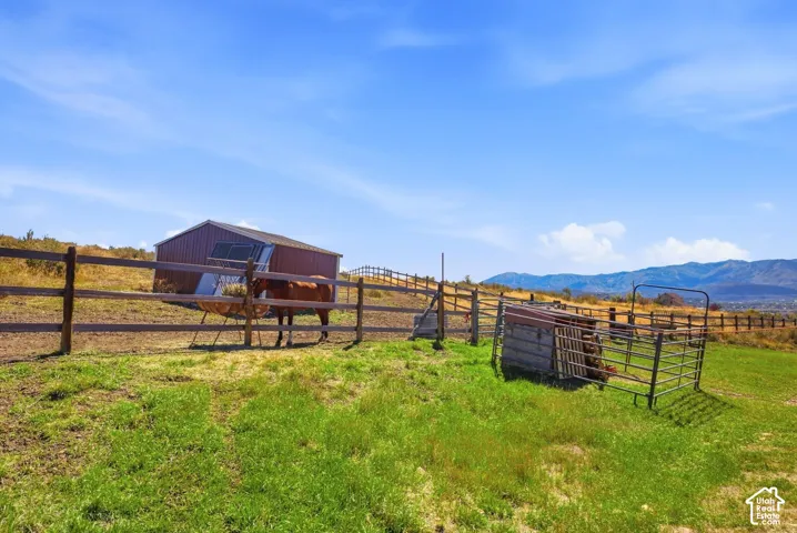 Spacious ranch property featuring multiple wooden post-and-rail fencing enclosures, a metal-roofed barn structure, and expansive pastureland