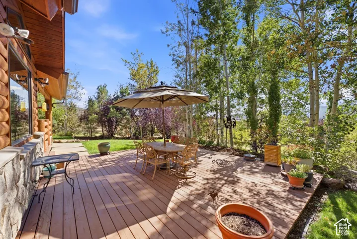 Log-style exterior with stone wainscoting and a wood-finish deck