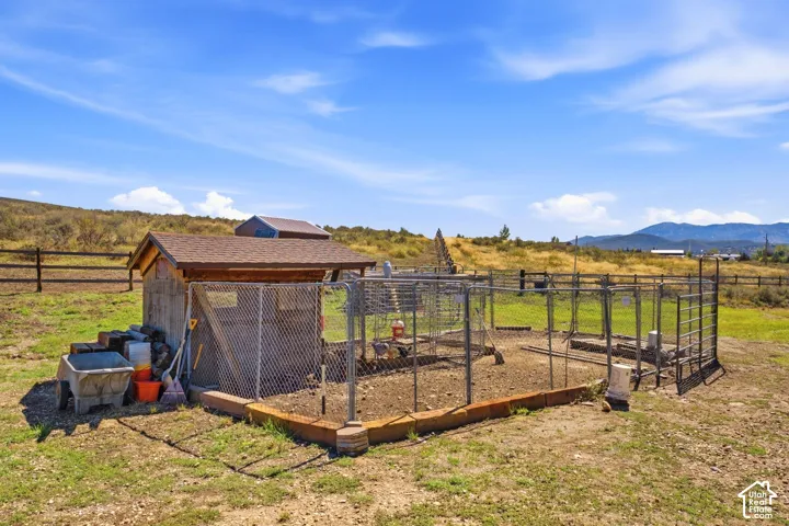 Outbuilding with a shingle roof and an attached fenced enclosure