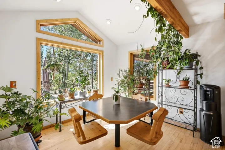 Vaulted ceilings with exposed wood beams, expansive picture windows, natural wood-finish flooring, and recessed lighting
