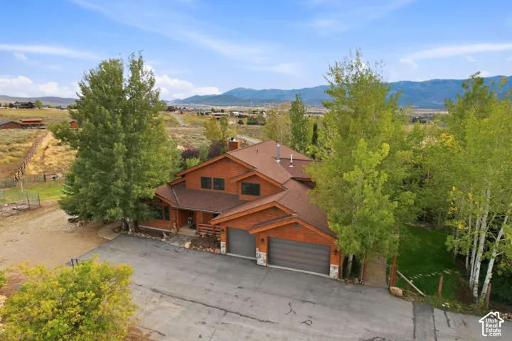 Wood-sided exterior with a multi-level roofline, attached two-car garage, and mature trees on the property