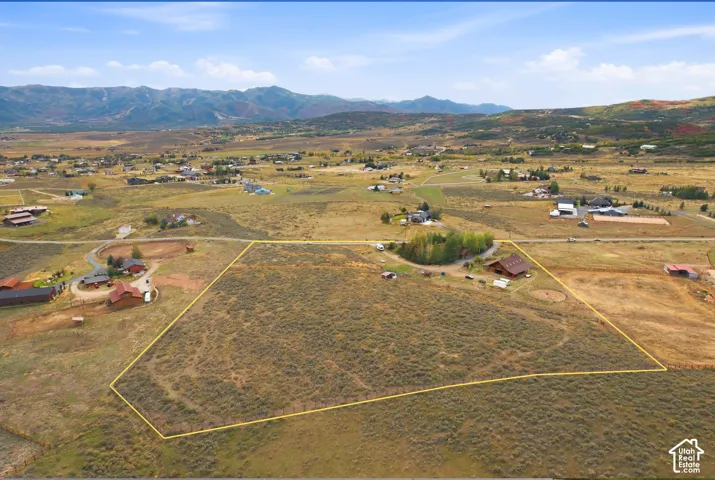 Expansive land parcel with surrounding mountain scenery and established neighboring properties
