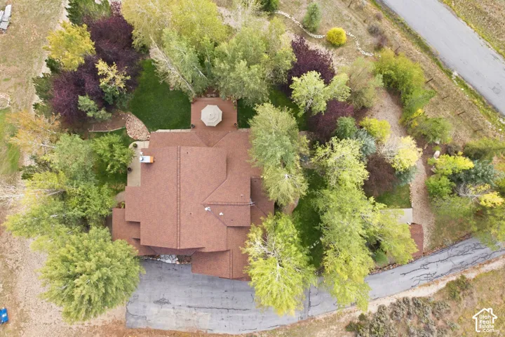 Terracotta-toned shingle roofing with multiple gables, surrounded by mature deciduous trees and a landscaped perimeter