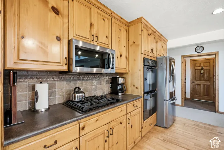 Wood-finish cabinetry, stainless steel appliances, built-in double ovens, gas range, and wood-finish flooring
