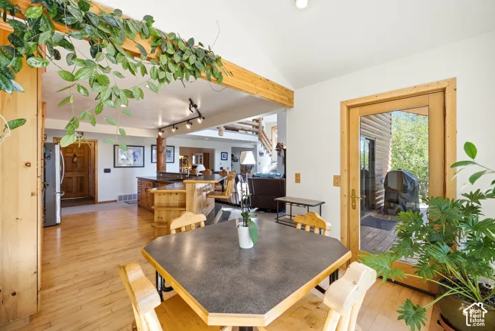 Vaulted ceiling with exposed wood beam, hardwood flooring, and a glass-paneled door