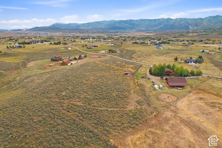 Expansive acreage featuring multiple structures, surrounding natural vegetation, and distant mountain ranges