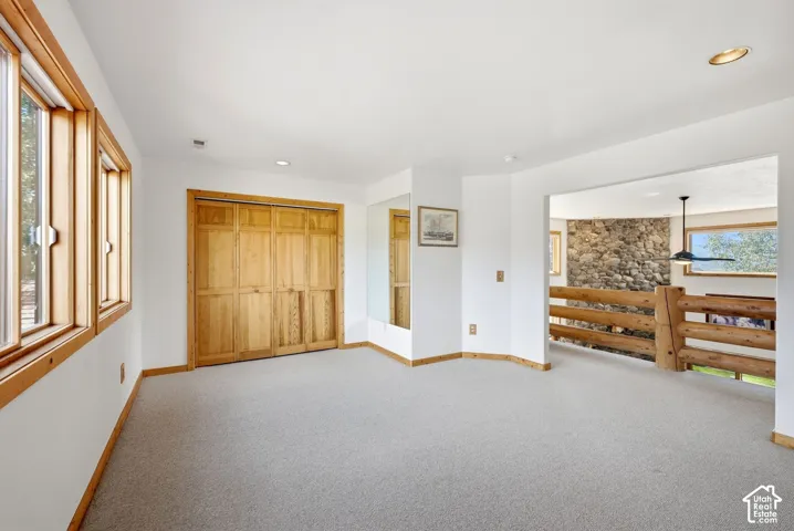 Carpet flooring, wood-framed windows, wood bi-fold closet doors, wood baseboards, and recessed lighting
