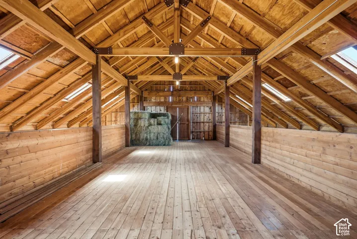 Hay Loft - Vaulted wood-plank ceiling with exposed beams, wood-plank flooring, and horizontal wood-plank walls
