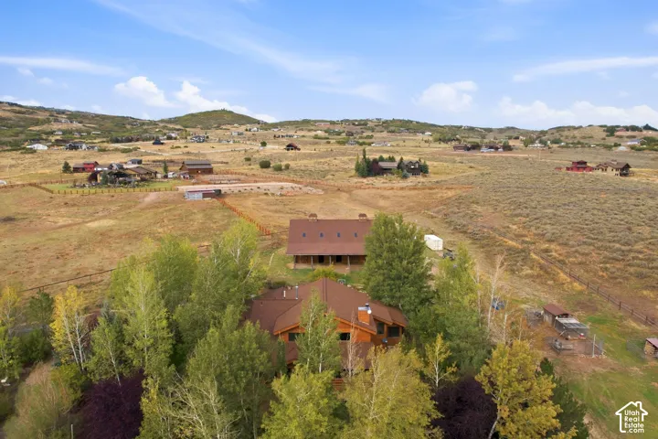 Expansive property featuring a main residence, secondary structure, mature trees, and natural terrain