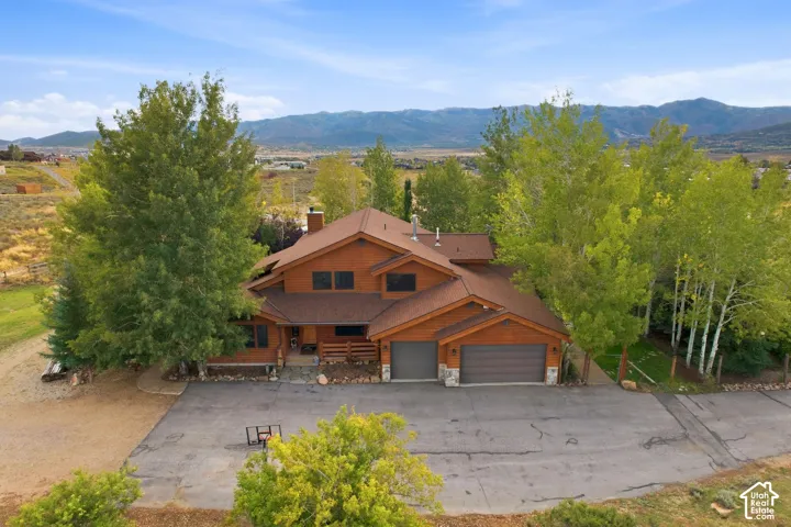 Wood-sided exterior with a two-car garage, prominent gabled roofline, and mature trees surrounding the property