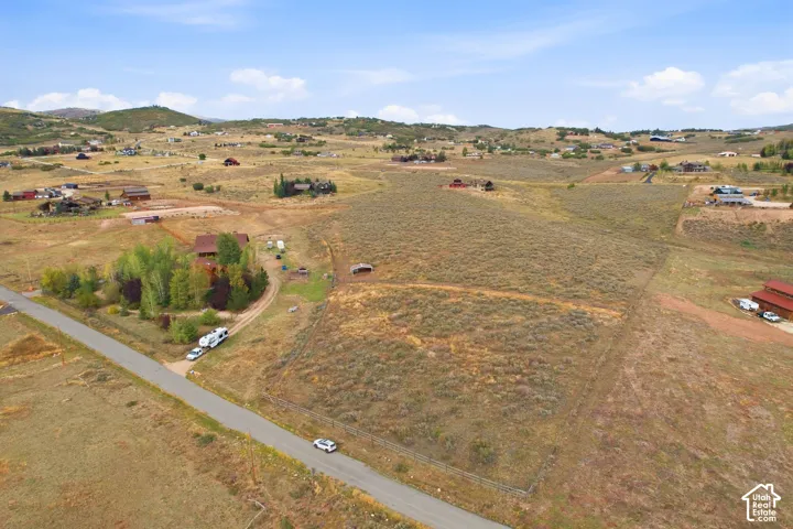 Expansive acreage featuring natural vegetation and surrounding hills, with a paved road bordering the property