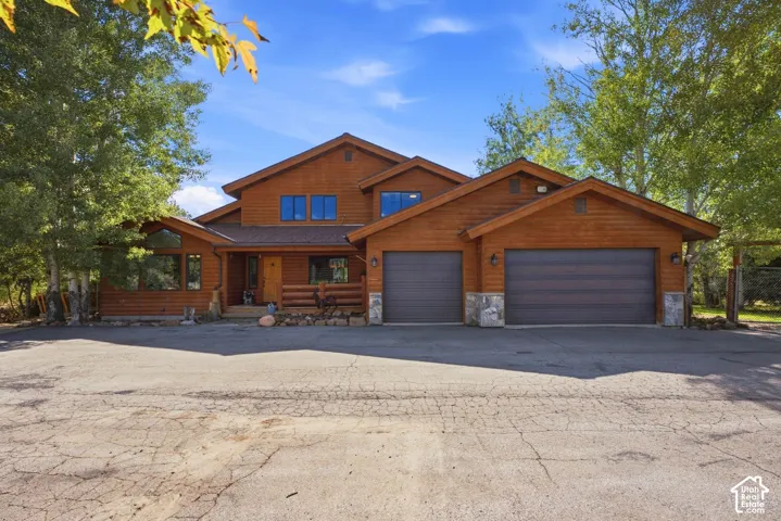 Wood-sided exterior with stone accents, an integrated two-car garage, and a covered porch