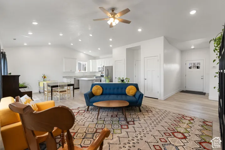 Recessed lighting, vaulted ceiling, wood-finish flooring, white cabinetry, and a ceiling fan with light