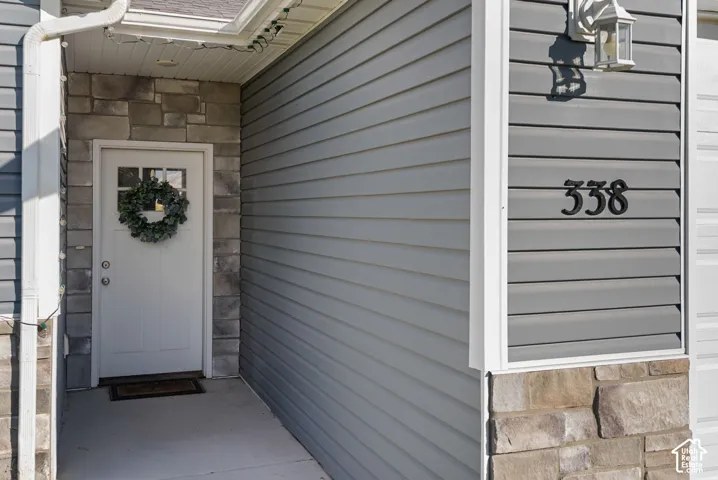 Entryway featuring a white paneled door with windowpanes, stone veneer accents, and light grey siding