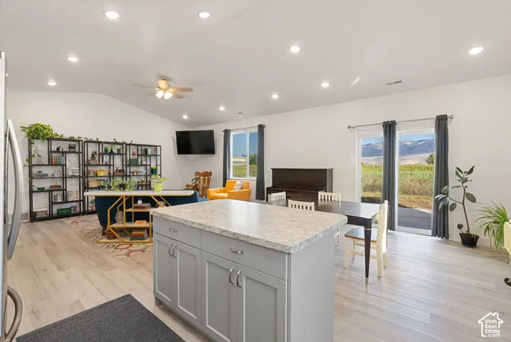 Open concept living area with vaulted ceilings, recessed lighting, wood-finish flooring, and a kitchen island with stone-finish countertop