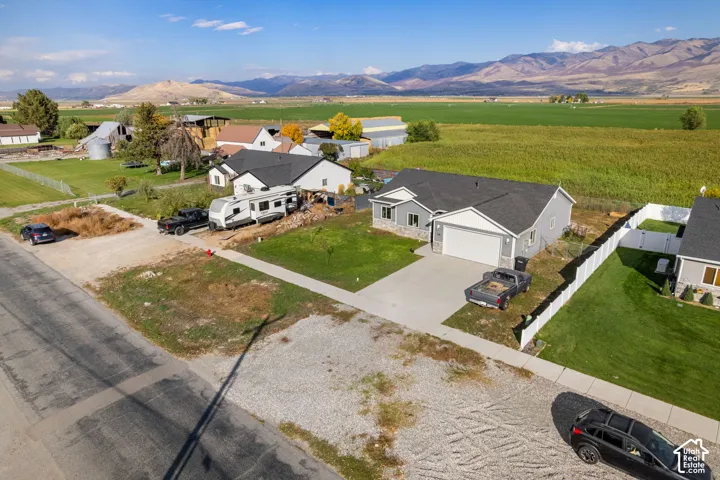 Siding exterior with stone accents, attached garage, concrete driveway, and a white picket fence