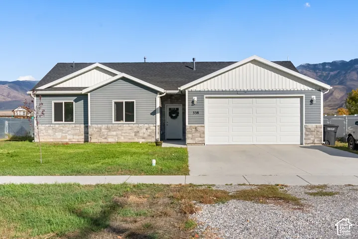 Single-story residence featuring a two-car garage, gray siding, and stone accents