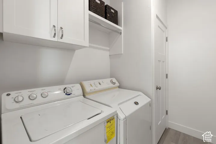 White shaker-style cabinetry, overhead shelving, white paneled interior door, and wood-finish flooring