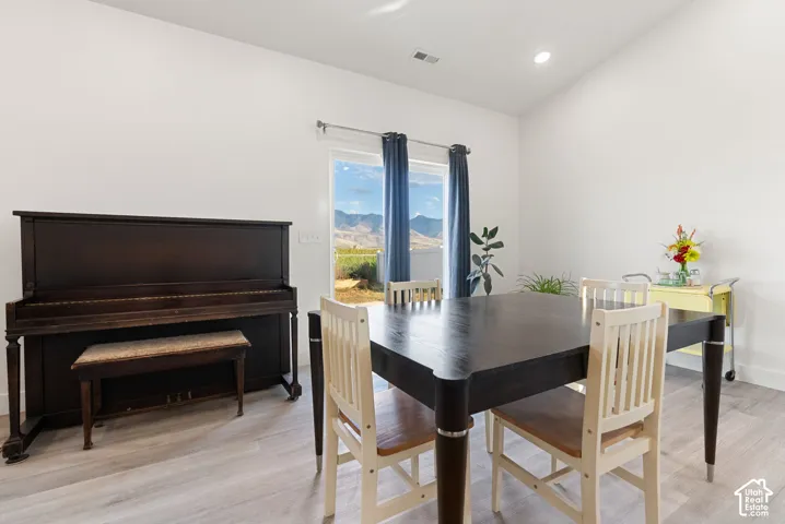 Recessed lighting, light wood-finish flooring, white walls, and a large window with mountain scenery