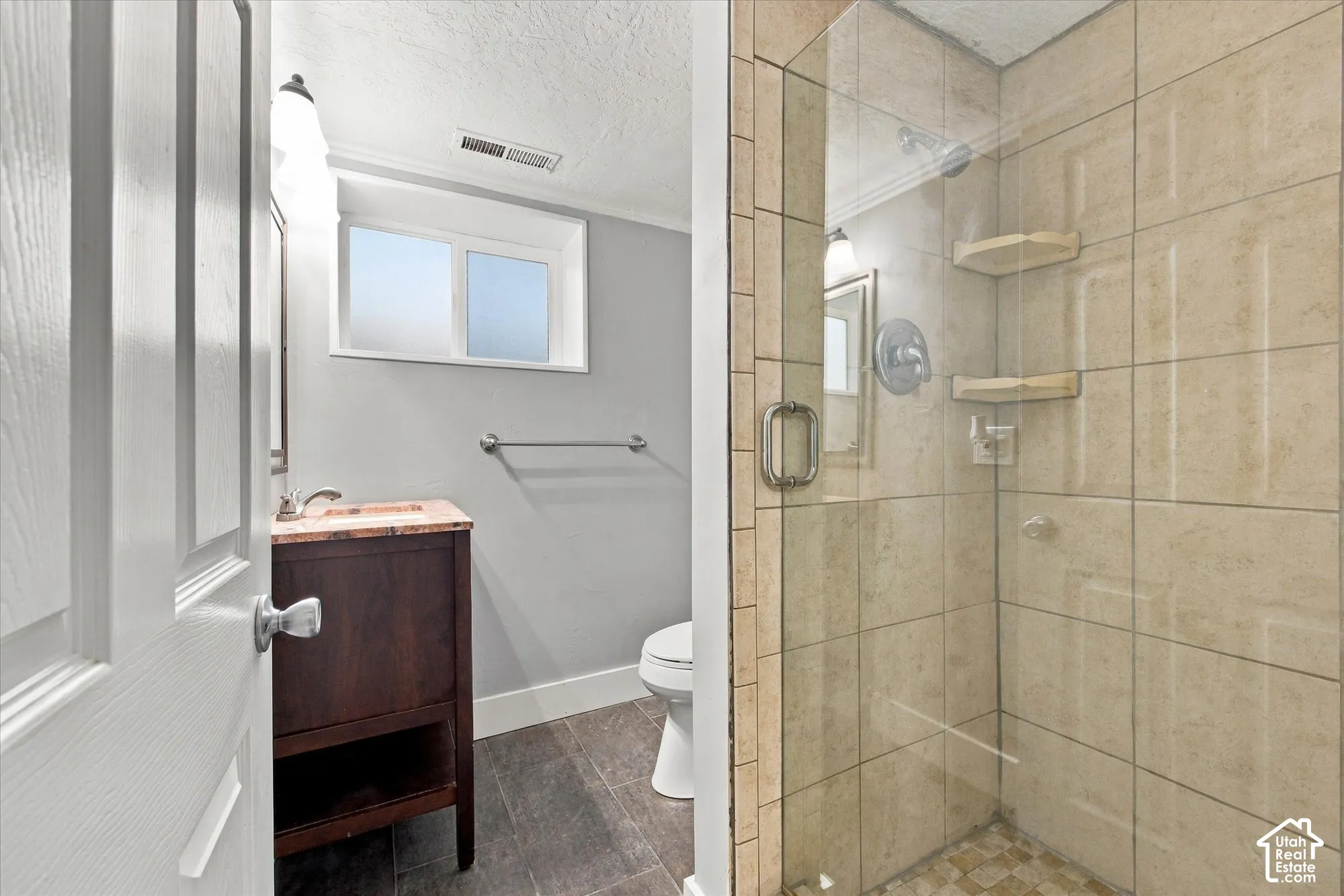 Fully tiled shower with glass enclosure, integrated shelving, and a pebble-finish floor