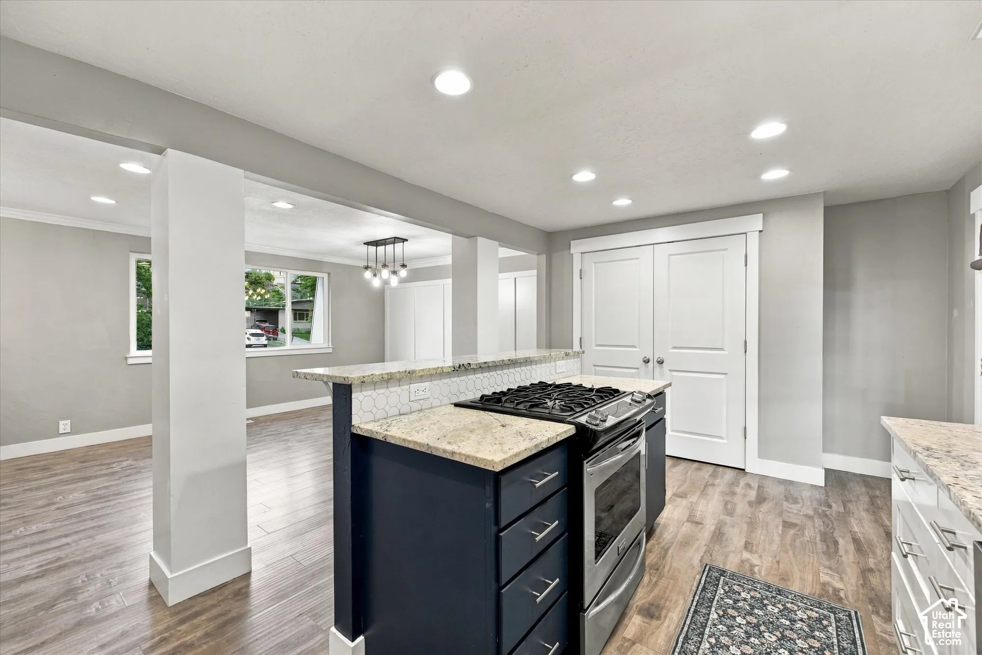 Kitchen island with a built-in range, stone countertops, hexagonal tile backsplash, and recessed lighting