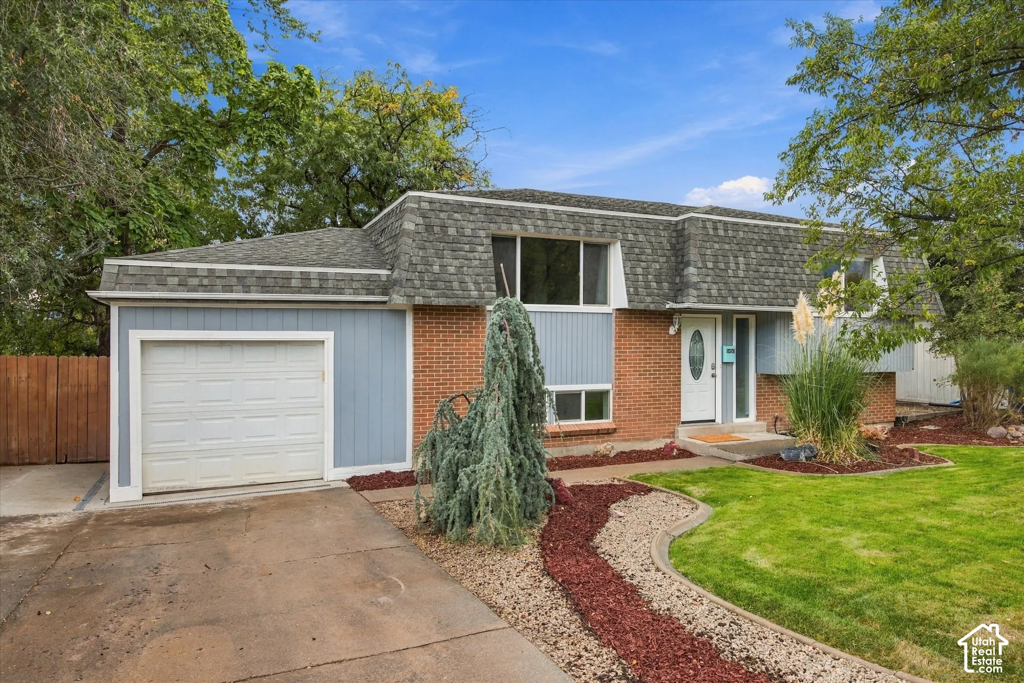 Siding exterior with brick accents, attached garage, and a peaked shingle roof