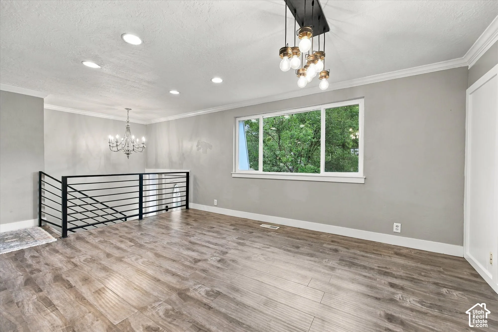 LVP flooring, contemporary black metal railing, prominent window, decorative chandelier, and recessed lighting