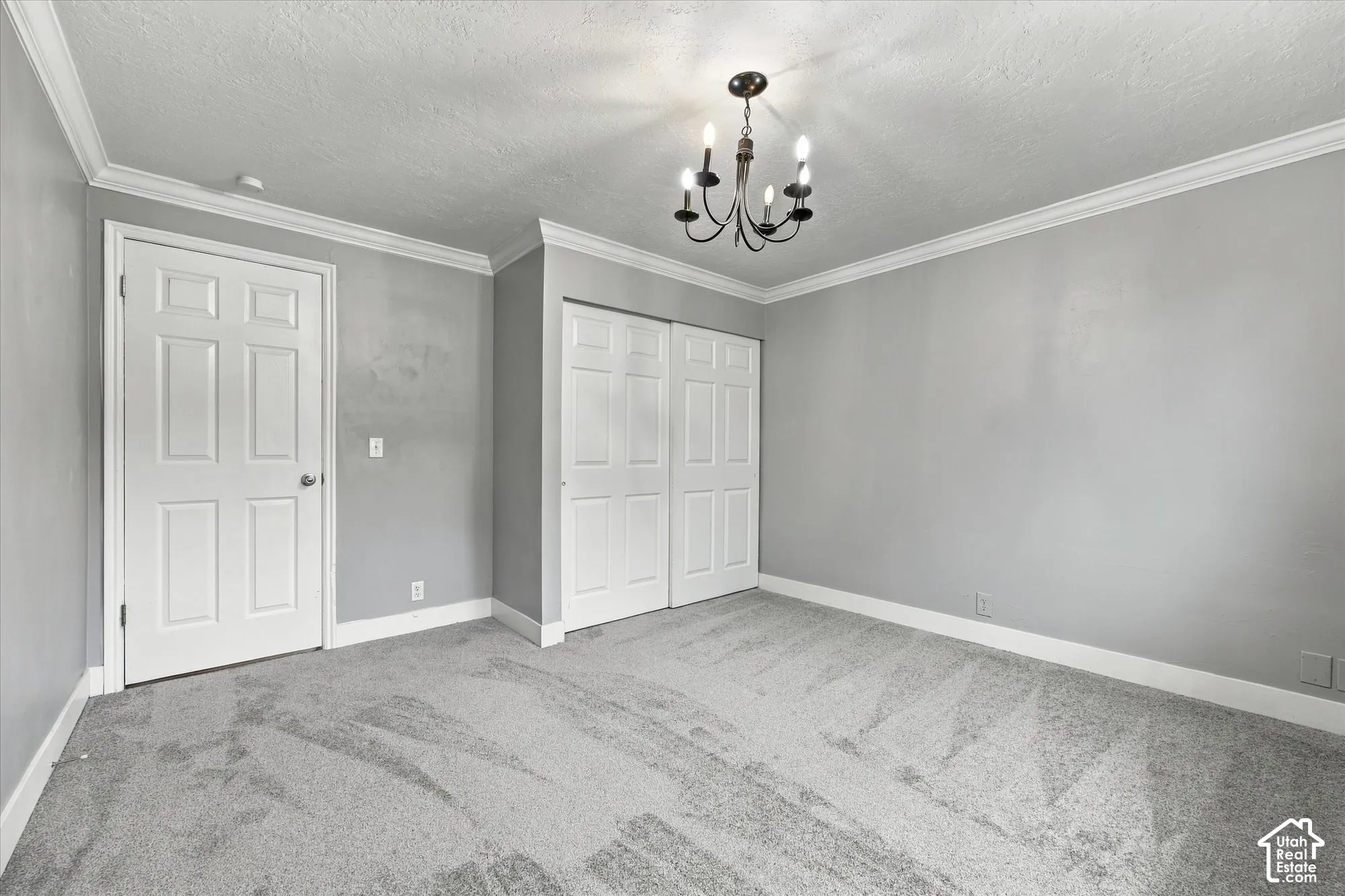 Crown molding, carpeted flooring, paneled interior door, bi-fold closet doors, and a chandelier lighting fixture