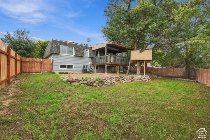 Expansive backyard with wood fencing, mature trees, and a raised deck