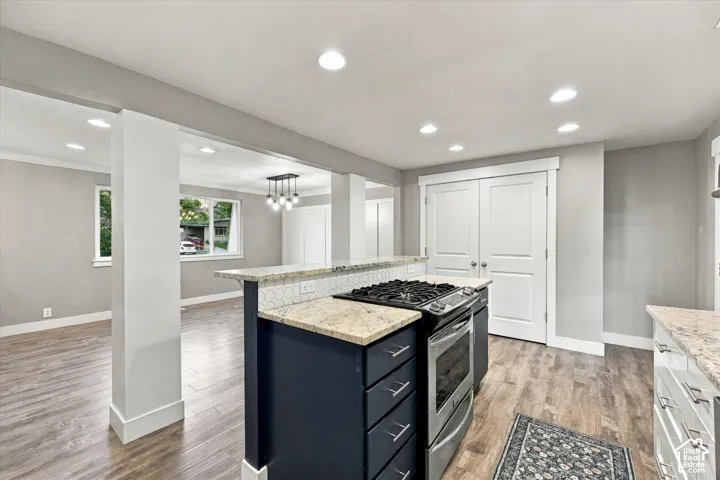 Kitchen island with a built-in range, stone countertops, hexagonal tile backsplash, and recessed lighting