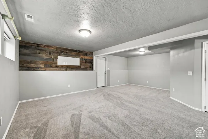 Recessed ceiling lighting, wood-finish accent wall, neutral tone carpeting, and painted drywall