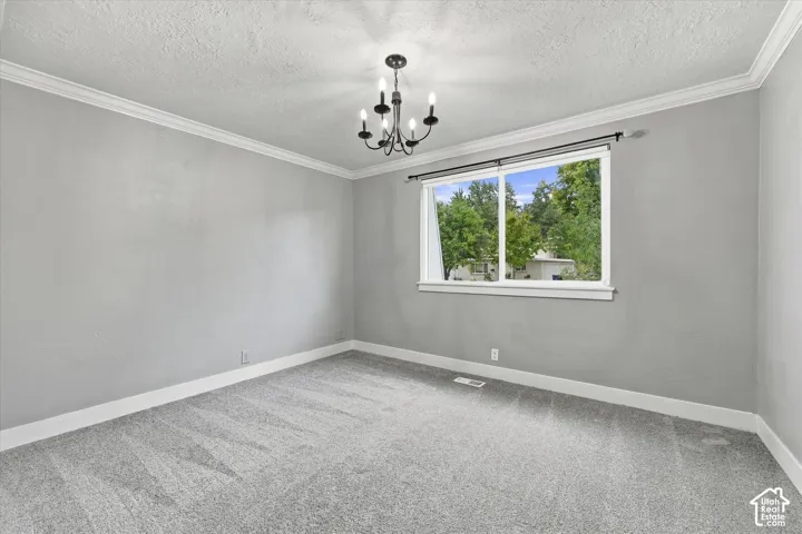 Wall-to-wall carpeting, crown molding, double-pane window, and a chandelier light fixture