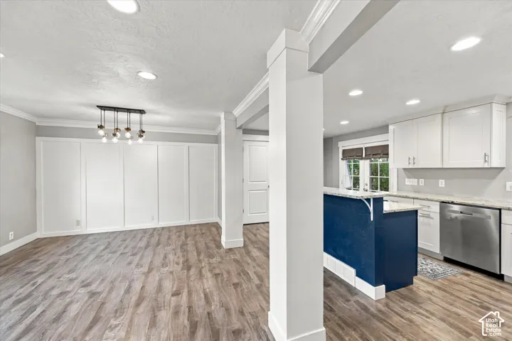 LVP flooring, recessed lighting, white kitchen cabinetry, stainless steel appliances, and a blue island base