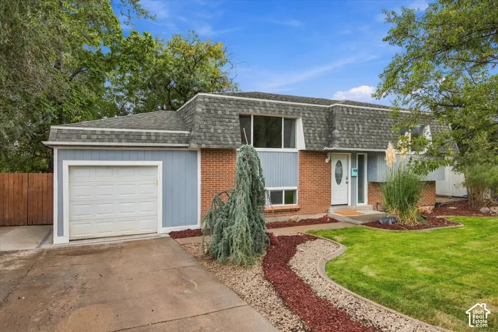 Siding exterior with brick accents, attached garage, and a peaked shingle roof