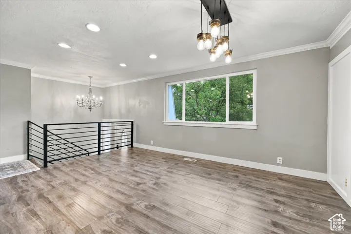 LVP flooring, contemporary black metal railing, prominent window, decorative chandelier, and recessed lighting