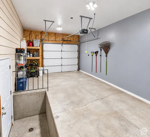 Attached garage featuring a concrete floor, painted walls, sectioned overhead door, and integrated ceiling lighting