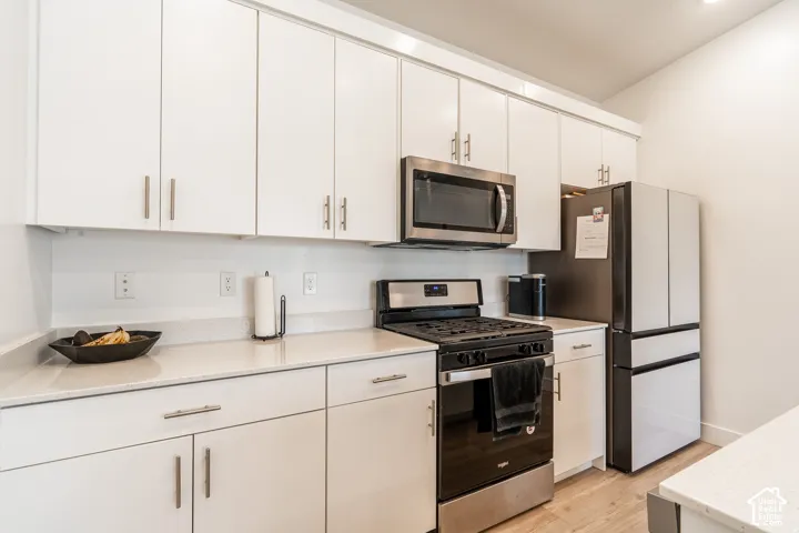 White cabinetry with brushed nickel hardware, light-toned countertops, and stainless steel appliances
