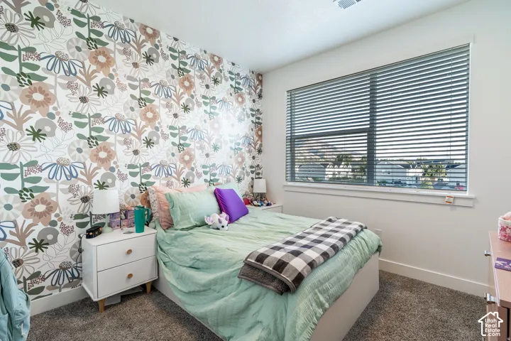 Patterned accent wall, window with horizontal blinds, neutral carpeting, recessed ceiling lighting, and white baseboards