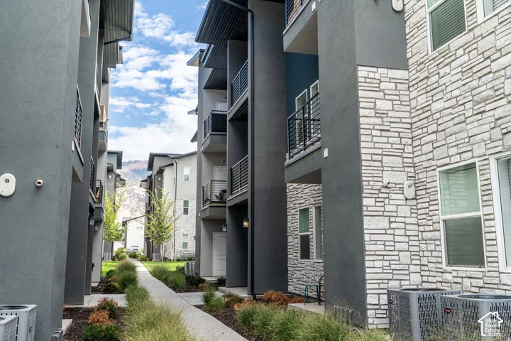 Modern courtyard walkway lined with contemporary multi-unit residences featuring mixed exterior finishes including charcoal cladding and stacked stone veneer
