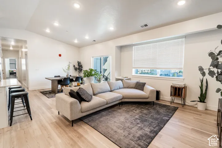 Spacious living area featuring wood-finish flooring, recessed lighting, a dining area, and a sliding glass door