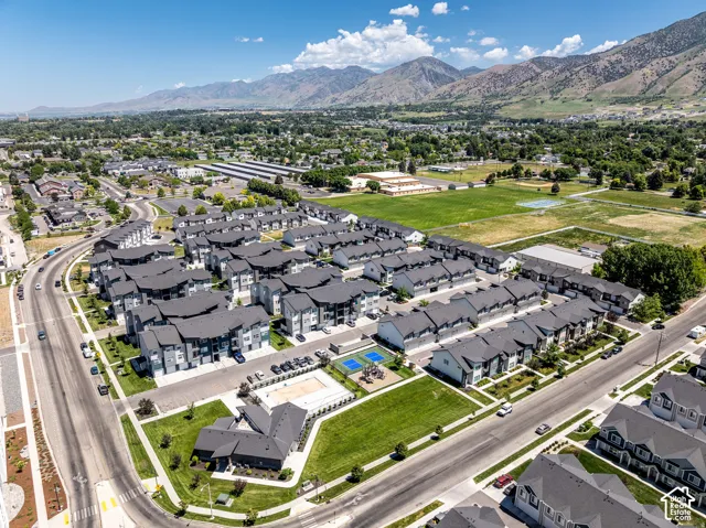 Aerial view of a modern residential community featuring contemporary architecture with dark exterior finishes, manicured landscaping, and resort-style amenities including a central pool and recreational areas