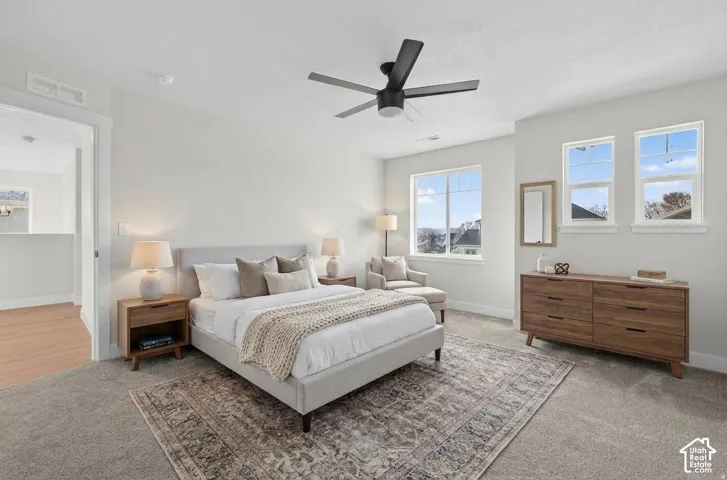 Bright room with a ceiling fan, three windows, and carpeted flooring