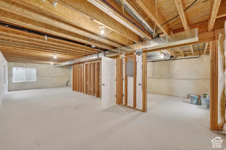 Unfinished basement with exposed ceiling joists, concrete flooring, and framed interior walls