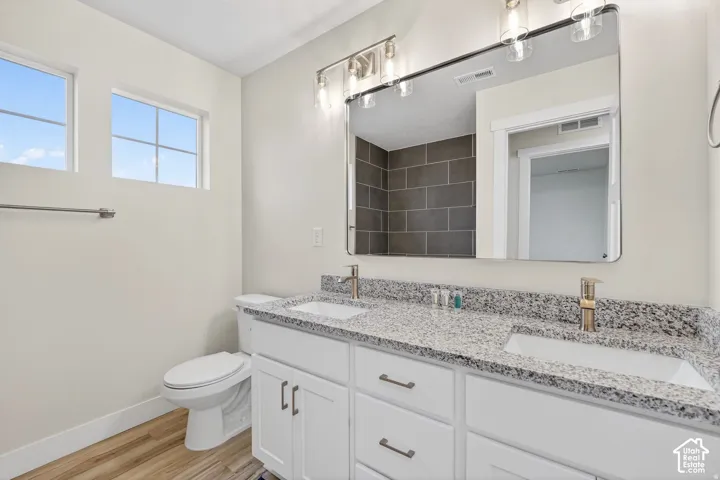 Dual vanity with white cabinetry, granite-finish countertop, and undermount sinks