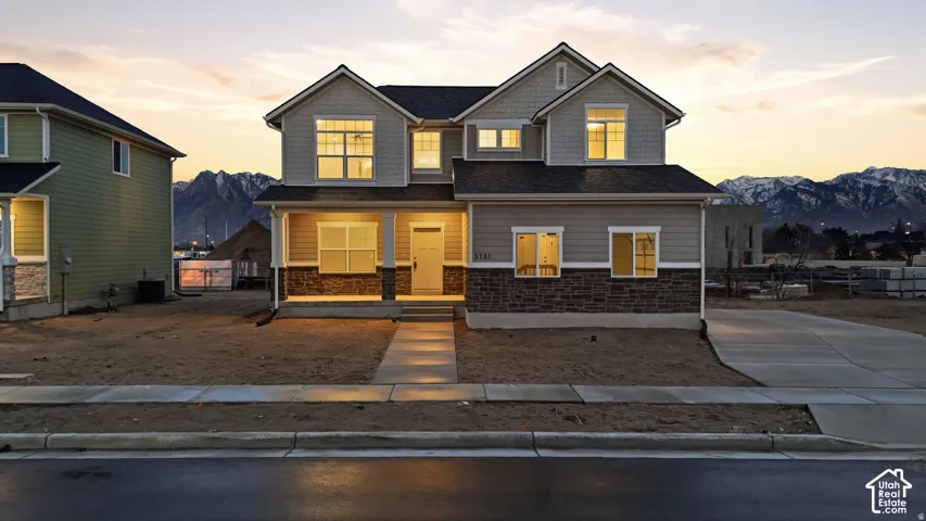 Two-story property featuring a covered porch, stone veneer and siding facade, and a paved driveway