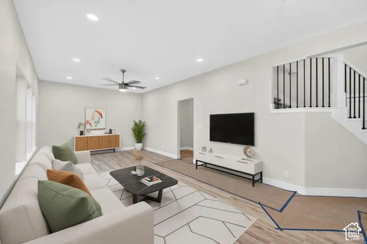 Recessed lighting, ceiling fan with light fixture, wood-finish flooring, and a staircase with black iron balusters
