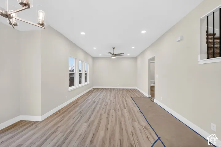 Recessed ceiling lighting, wood-finish flooring, multiple windows, ceiling fan, and modern chandelier